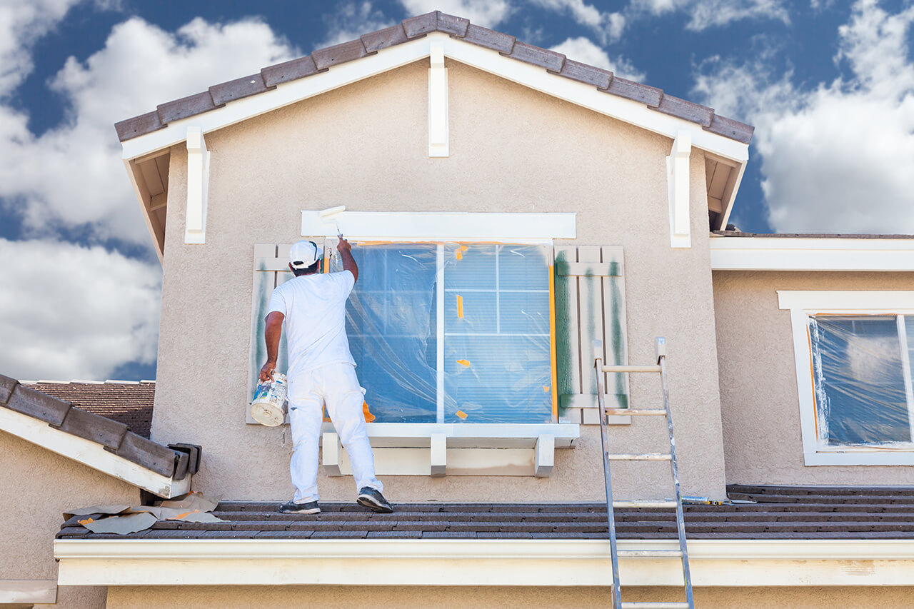 professional painting the exterior of a stucco home