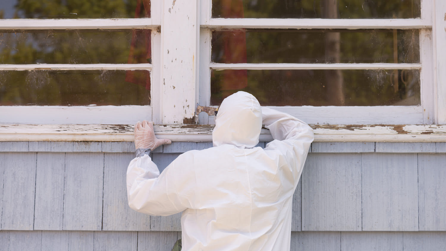 A contractor removing lead paint from the exterior of a house