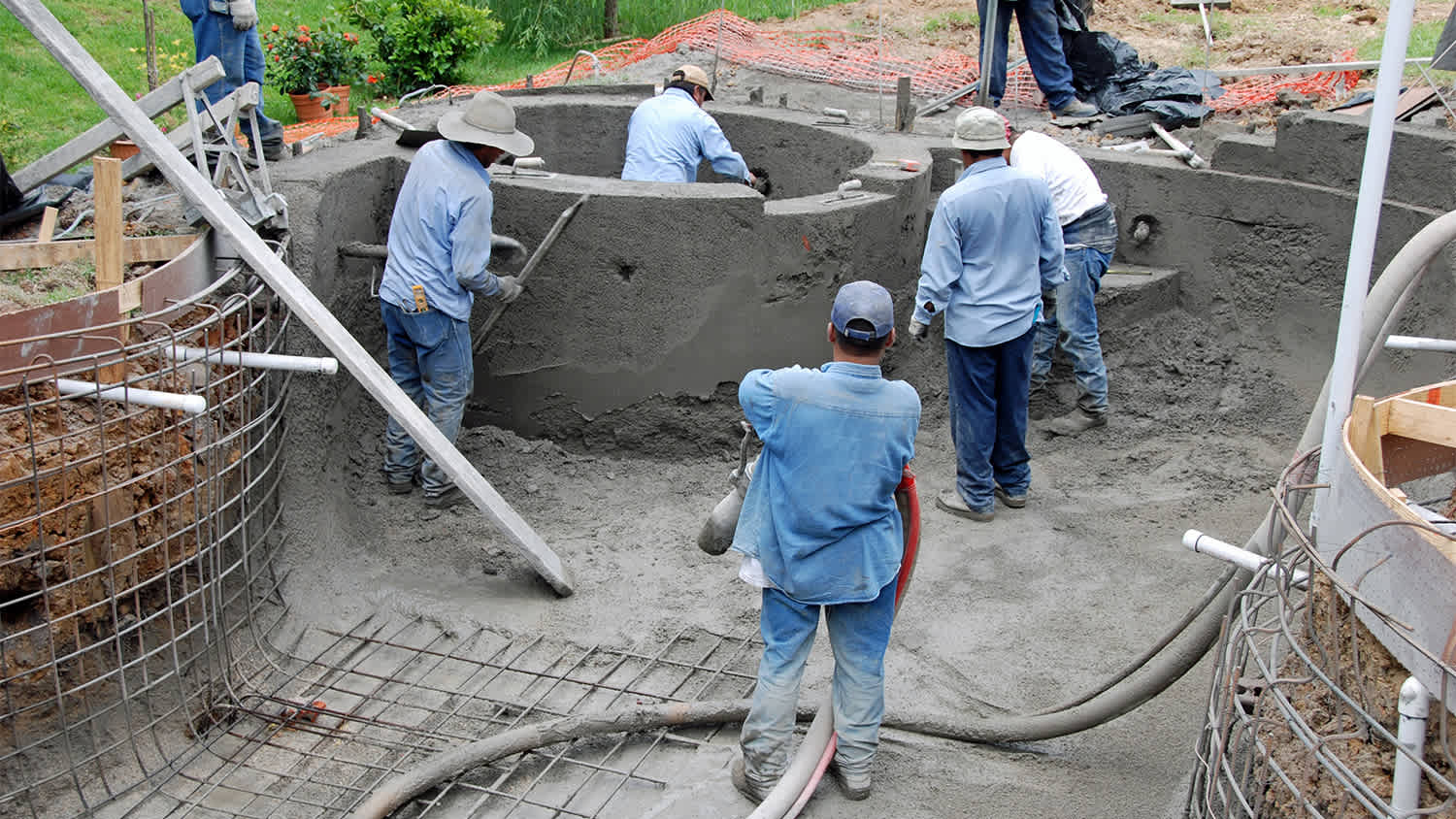 construction workers installing pool in backyard