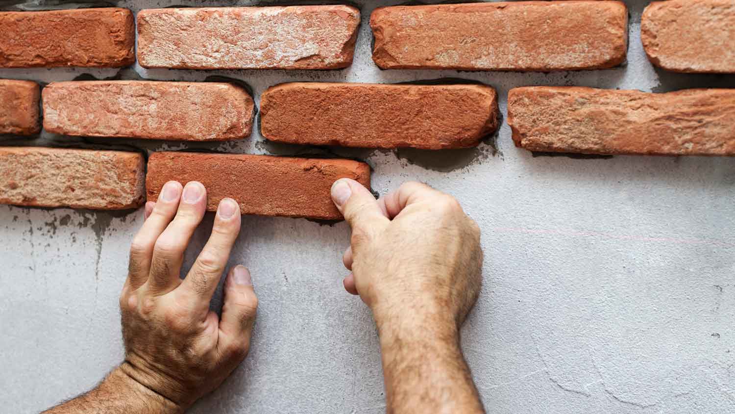 A man placing brick veneer siding