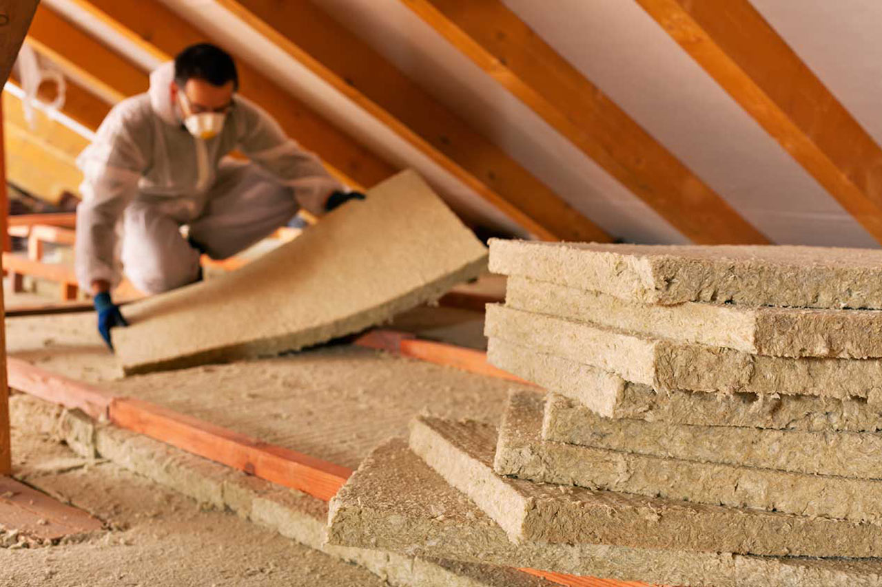 A professional removing insulation panels from attic